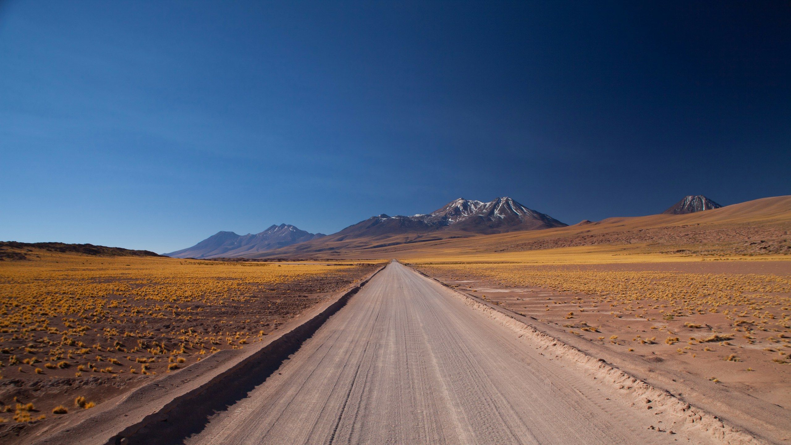 A dirt road across the Atacama altiplano, heading towards the volcanoes.