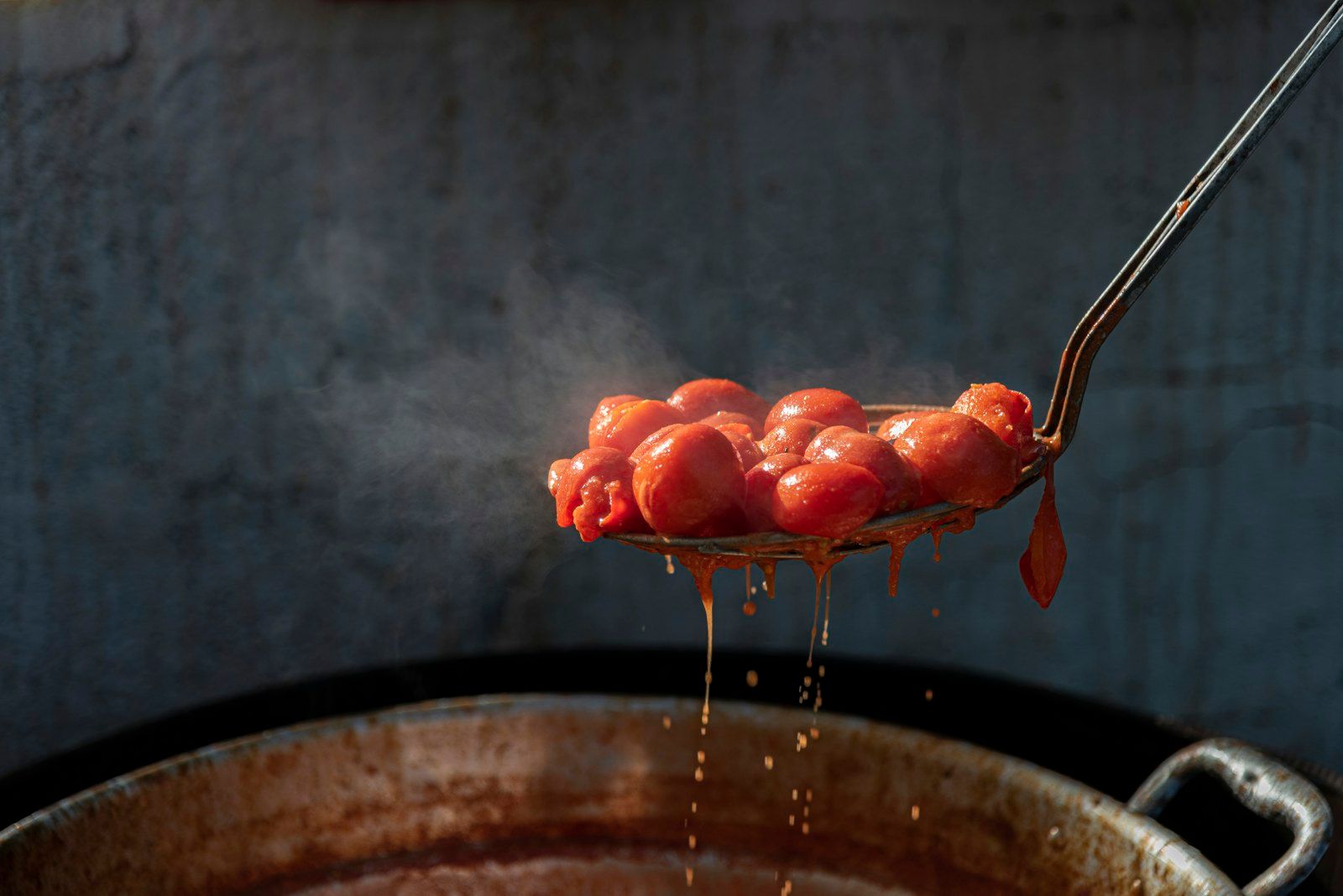 Tomatoes lifted from the pot on a slotted spoon, ready for the sauce, in Alberobello.