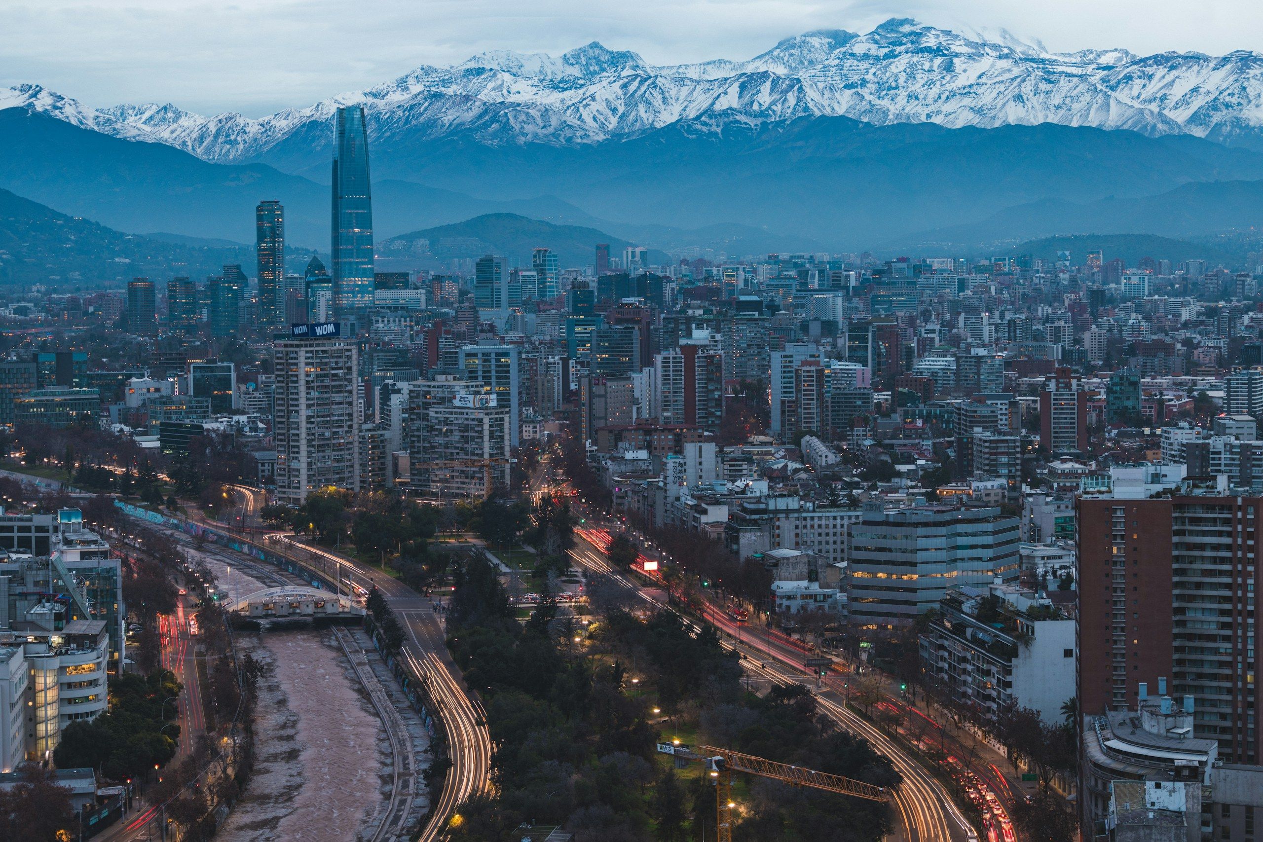 Santiago at dusk, with the Mapocho River, the city lights and the snow-capped Andes behind.